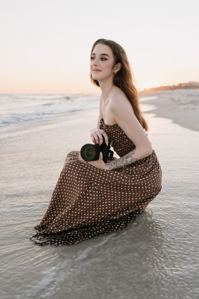 Pensacola wedding photographer crouching in the water at Pensacola Beach.